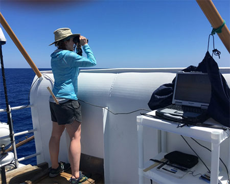 Pamela looking through binoculars onboard research vessel